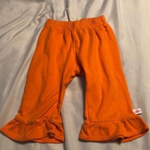 Orange pants with ruffle at bottom.